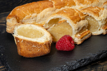 Fresh baked Dutch filled spicy cookies from puff pastry with almonds in autumn colors on dark stone