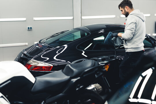 Ceramic paint protection. Man during car detailing. Process of applying ceramic coating onto black sports car with a microfiber cloth. High quality photo