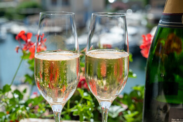 Drinking of French brut champagne sparkling wine in glasses in yacht harbour of Port Grimaud near Saint-Tropez, French Riviera vacation, France