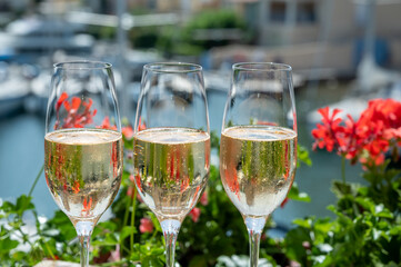 Drinking of French brut champagne sparkling wine in glasses in yacht harbour of Port Grimaud near Saint-Tropez, French Riviera vacation, France