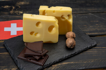 Swiss food, medium-hard cow milk cheese Gruyere, appenzeller, emmentaler with holes, dark swiss chocolate and flag of Switzerland