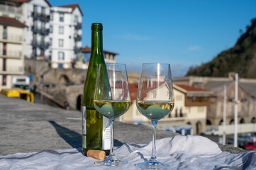 Tasting of txakoli or chacolí slightly sparkling very dry white wine produced in Spanish Basque Country with view on old port and village Getaria, Spain