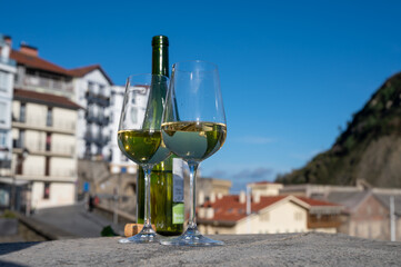 Tasting of txakoli or chacolí slightly sparkling very dry white wine produced in Spanish Basque Country with view on old port and village Getaria, Spain