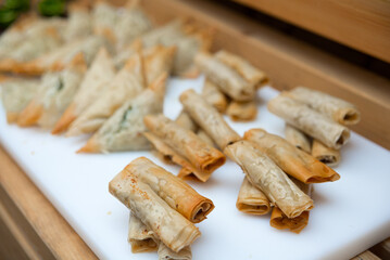 Filo puff pastry rolls with toppings fried in oil, assortment of appetizers on the board