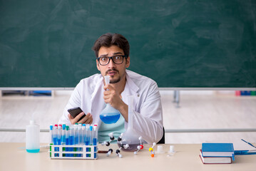 Young male chemist in front of blackboard