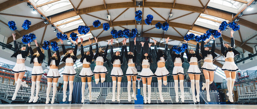 Full shot. A group of cheereladers jumping and thowing their pom-poms up. Sport conept. High quality photo