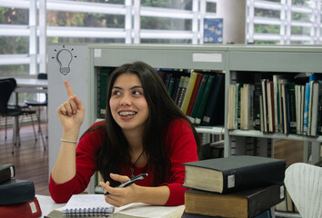 Chica estudiante vestida de rojo teniendo una idea en la biblioteca