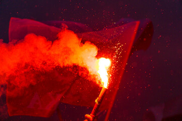 Red burning flare and polish flags
