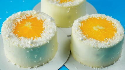 Small cakes with orange and coconut on a blue background.