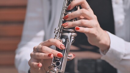 A girl plays the clarinet in the park in the summer.