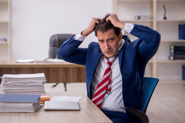 Young male employee and too much work in the office