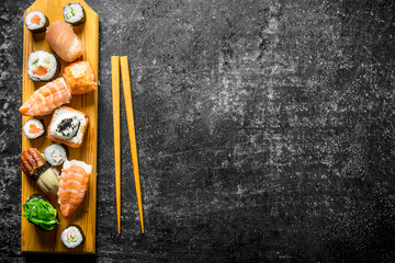 Fresh sushi rolls on wooden cutting Board with chopsticks.