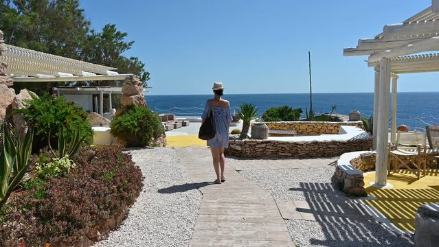 giovane donna di spalle cammina lungo un villaggio in riva al mare