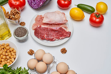 food that includes meat, eggs, beans, tomatoes, and other ingredients on a white background with space for text