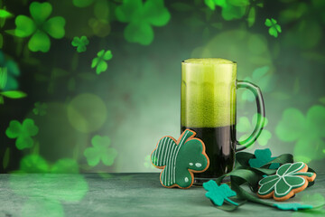 Glass of beer and gingerbread cookies on green background. St. Patrick's Day celebration
