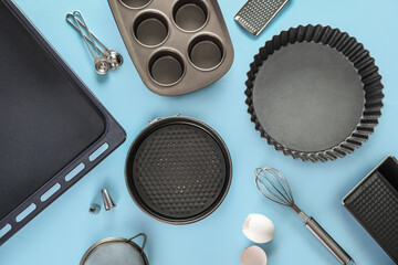 Baking tray with forms and utensils on blue background