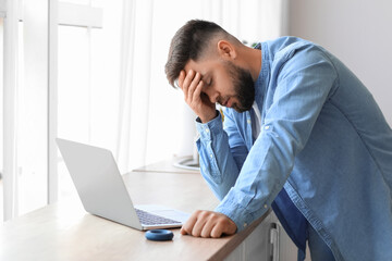 Worried young man with laptop at home