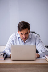 Young male teacher sitting in the classroom