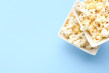 Ceramic bowls with tasty popcorn on color background