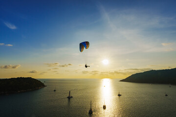 Viewpoint Laempromthep, Phuket, Thailand. Silhouette, Paragliding extreme sport activity and Sailboat tour to watch sunset in the evening on lifestyle vacation. Leave free space for text input.