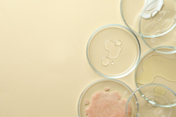 Many Petri dishes and cosmetic products on beige background, flat lay. Space for text