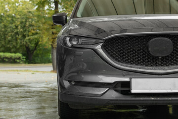 Black dirty car at outdoor carwash, closeup