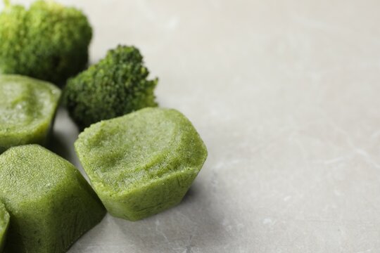 Frozen broccoli puree cubes with ingredient on marble table, closeup. Space for text