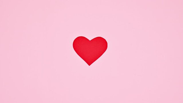 Hand touching red heart on pastel pink background. Valentine's day stop motion. Flat lay