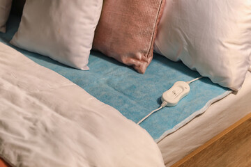 Bed with electric heating pad in bedroom at night, closeup