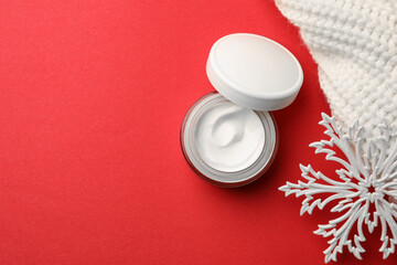 Obraz na płótnie Canvas Winter skin care. Flat lay composition with hand cream and decorative snowflake on red background. Space for text