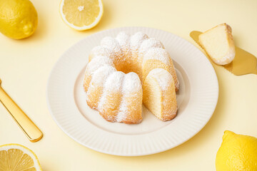 Plate with delicious cake and lemons on yellow background