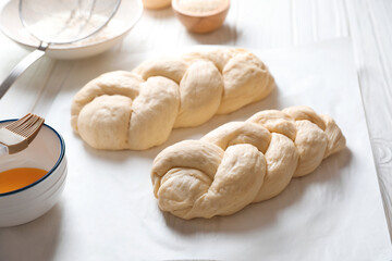 Homemade braided breads and ingredients on white wooden table, above view. Cooking traditional Shabbat challah