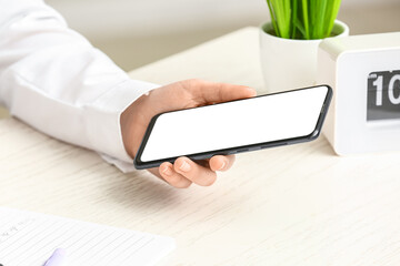 Female hand with modern mobile phone on table, closeup