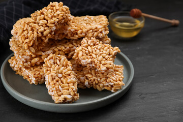 Plate with puffed rice bars (kozinaki) on black table, closeup. Space for text
