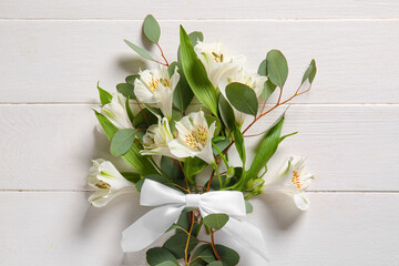 Beautiful bouquet of alstroemeria flowers and eucalyptus branches on light wooden background