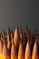 Many sharp graphite pencils on grey background, space for text