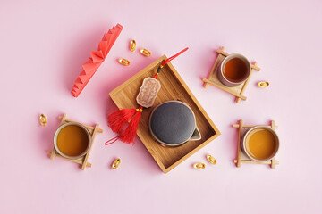 Box with teapot, cups of tea and Chinese symbols on pink background