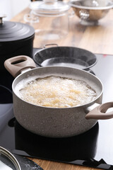 Cooking pot with boiling pasta on stove in kitchen, closeup