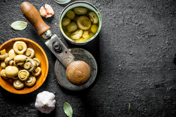 Canned mushrooms in a tin and on a plate of garlic.