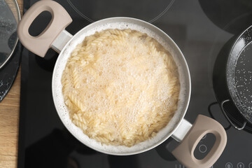 Cooking pot with boiling pasta on stove, closeup