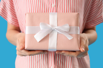 Woman holding gift on blue background. Valentine's Day celebration