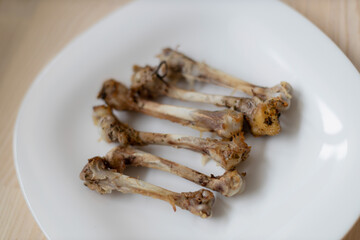 Multiple chicken bones on a white plate