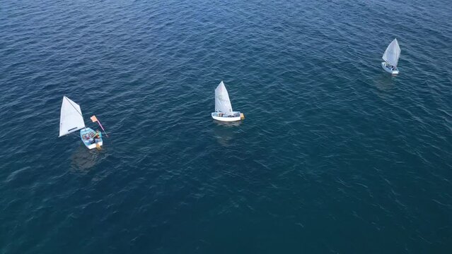Junior sailors sport competition. Junior yacht club regatta in the open sea. Junior training course on sailboats. Aerial drone video. 