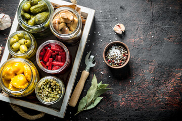 Jars of various preserved vegetables on tray.