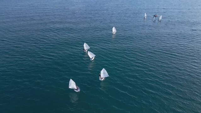 Junior sailors sport competition. Junior yacht club regatta in the open sea. Junior training course on sailboats. Aerial drone video. 