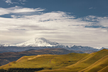 Big mountain Elbrus against the blue sky. View from a large plateau and steep cliffs.