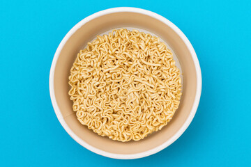 Opened Package with Uncooked Instant Noodles on Blue Background. Raw Pasta. Dry Asian Fast Food. Quick Lunch