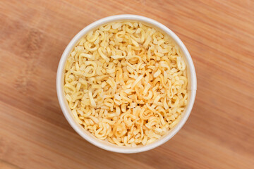 Instant Noodles in Disposable Cup on Wooden Background - Top View. Asian Fast Food. Quick Lunch