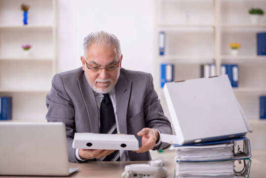 Old male employee eating pizza in the office - Powered by Adobe