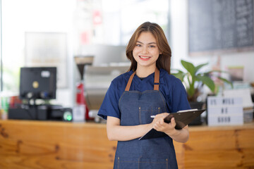 attractive young beautiful asian woman employee or small business owner waitress in an apron standing in coffee shop counter, Coffee Asian SME Small business owner concept 